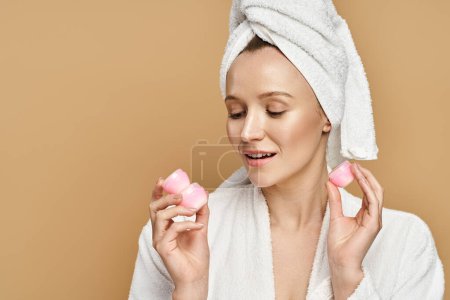Una belleza natural con una toalla en la cabeza sostiene dos cremas en una pose caprichosa.