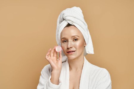 Una mujer con una toalla en la cabeza sostiene juguetonamente la crema, exudando belleza natural y gracia.