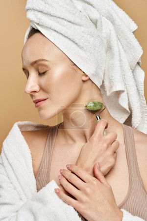 Téléchargez les photos : Une femme inclinée avec une serviette délicatement enroulée autour de sa tête, mettant en valeur la beauté naturelle et la grâce. - en image libre de droit