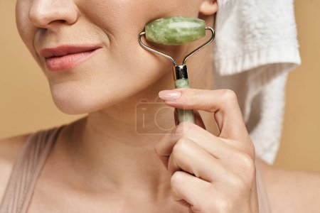 A natural beauty holds face roller in her right hand.