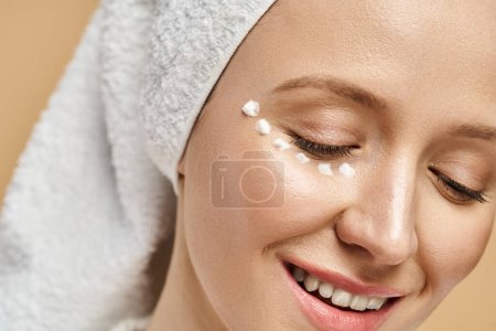 Téléchargez les photos : Une femme sereine et séduisante avec une serviette enroulée autour de sa tête souriant joyeusement. - en image libre de droit