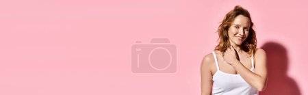 Photo for An attractive woman with natural beauty striking a pose in front of a vibrant pink wall. - Royalty Free Image