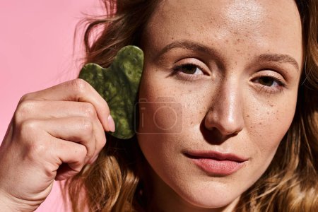 Photo for An attractive woman with natural beauty holding a gua sha up close. - Royalty Free Image
