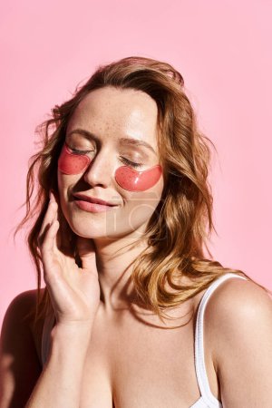 A natural beauty woman poses actively with a red eye patch on her face, wearing a white top.