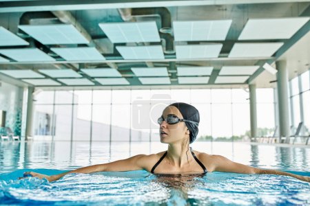 Photo for Female swimmer wearing goggles, gliding gracefully in swimming pool. - Royalty Free Image