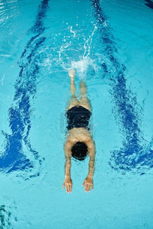 Eine Frau in Badebekleidung schwimmt friedlich in einem Pool mit blauem Wasser