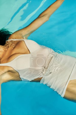 Ausgeschnittene Ansicht einer entspannten jungen Afroamerikanerin, die in ihrem Badeanzug im Pool schwimmt