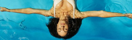 top view of young african american woman swimming on her back in blue pool water, tranquil banner