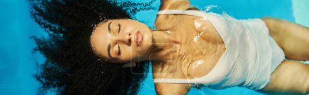 top view of relaxed african american woman swimming on her back in blue pool water, serenity banner