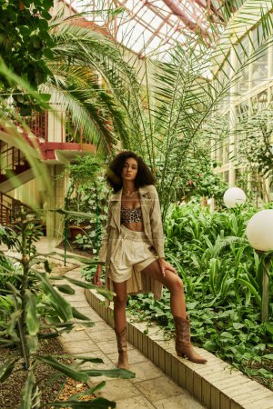 Téléchargez les photos : Trendsetter dans le jardin botanique, mélange de haute couture avec la nature sauvage, femme afro-américaine - en image libre de droit