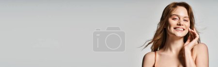 Téléchargez les photos : Portrait de beauté de femme souriante avec un maquillage à la mode, regardant la caméra sur fond gris, bannière - en image libre de droit