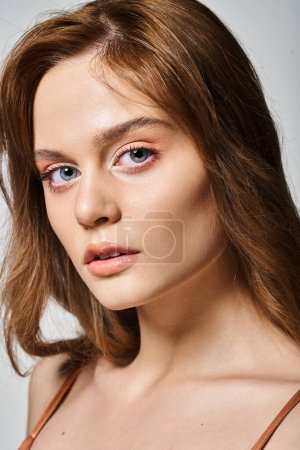 Photo for Closeup portrait of attractive girl with peach natural makeup with perfect skin on grey background - Royalty Free Image