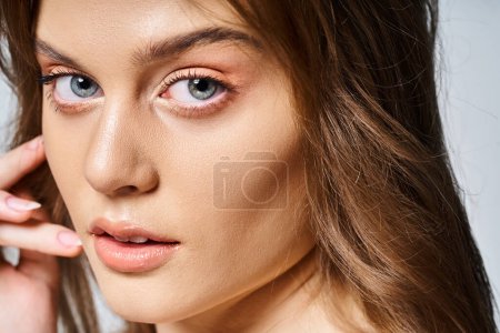 Closeup portrait of pretty woman with peach natural makeup with perfect skin on grey background