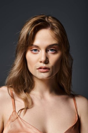Schönheitsporträt einer attraktiven sinnlichen jungen Frau mit blauen Augen vor dunkelgrauem Hintergrund