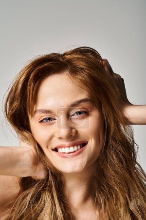 Téléchargez les photos : Portrait de beauté de femme souriante avec un maquillage naturel, regardant la caméra toucher ses cheveux - en image libre de droit