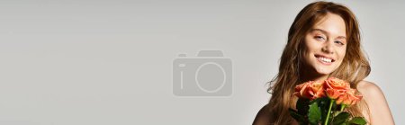 Téléchargez les photos : Portrait de femme souriante aux yeux bleus, tenant des roses pêche posant sur fond gris, bannière - en image libre de droit