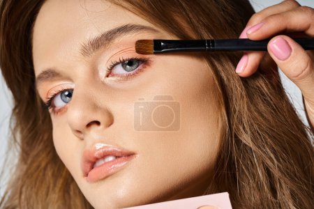 Photo for Closeup beauty portrait of pretty woman with makeup and brush applying eyeshadow on grey background - Royalty Free Image