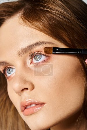 Photo for Closeup beauty portrait of woman with makeup and brush applying eyeshadow on grey background - Royalty Free Image