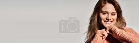 Téléchargez les photos : Femme souriante regardant la caméra avec un maquillage naturel, portant un pull, touchant le menton, bannière - en image libre de droit