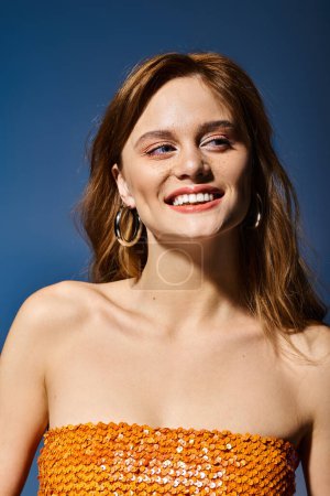 Téléchargez les photos : Femme souriante confiante regardant loin avec un maquillage naturel de pêche nue, sur fond bleu - en image libre de droit