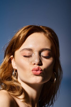 Closeup shot of pretty attractive woman sending blow kisses to camera, on blue background