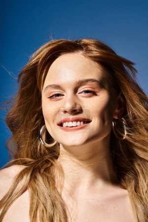 Foto de Retrato de belleza de mujer atractiva sonriente mirando a la cámara, sobre fondo azul - Imagen libre de derechos