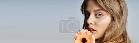 Photo for Closeup beauty shot of woman with peach makeup eyeliner, gerbera daisy, face jewels, banner - Royalty Free Image