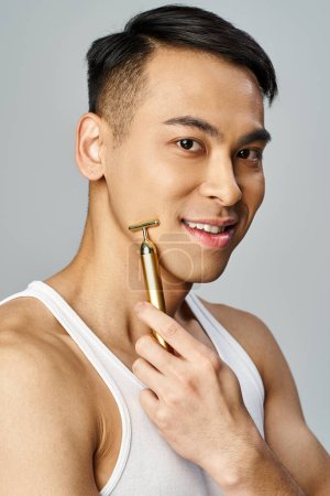 Un hombre asiático sosteniendo un objeto de navaja de oro en un estudio gris, mostrando riqueza y elegancia.