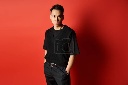 A stylish and handsome Asian man stands confidently in front of a striking red wall in a studio setting.