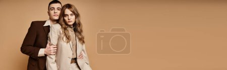 Photo for Appealing couple in chic suits posing together and looking at camera on pastel backdrop, banner - Royalty Free Image