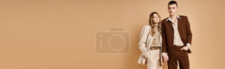 chic young woman in stylish suit posing with her handsome boyfriend and looking at camera, banner