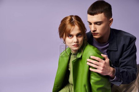 Téléchargez les photos : Belle femme élégante en veste verte assise sur le sol avec son petit ami et regardant la caméra - en image libre de droit