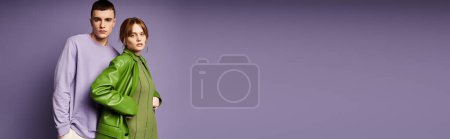Foto de Pareja amorosa en ropa vibrante posando juntos sobre fondo púrpura y mirando a la cámara, pancarta - Imagen libre de derechos