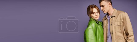 Téléchargez les photos : Femme élégante en veste verte regardant la caméra près de son petit ami aimant sur fond violet, bannière - en image libre de droit
