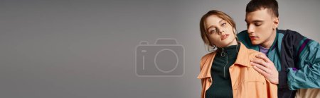 Téléchargez les photos : Jolie femme dans bomber regardant caméra à côté de son beau petit ami sur fond gris, bannière - en image libre de droit