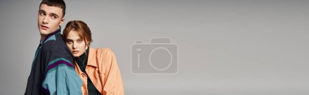 Téléchargez les photos : Séduisante femme dans bombardier regardant la caméra à côté de son beau petit ami sur fond gris, bannière - en image libre de droit
