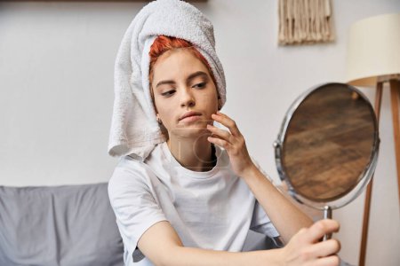 Téléchargez les photos : Personne extravagante attrayante avec une serviette de cheveux blancs regardant dans le miroir pendant la routine du matin à la maison - en image libre de droit