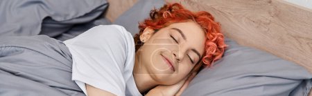 Foto de Bien parecido pelirrojo queer persona en la ropa de casa siesta en su cama en casa, tiempo libre, bandera - Imagen libre de derechos