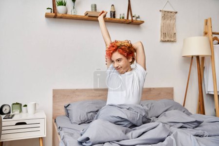 extravagant pretty queer person in casual attire waking up and stretching in her bed, leisure time