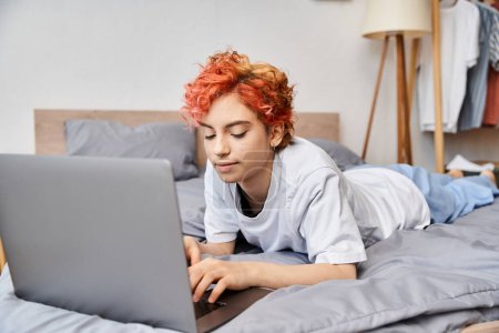 joyous appealing queer person in cozy homewear lying in bed and surfing in internet, leisure