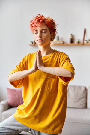 attractive red haired queer person in vivid outfit meditating with closed eyes while at home