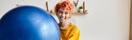 Photo for Joyous queer person in comfy attire exercising with fitness ball and smiling at camera, banner - Royalty Free Image