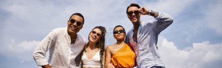 Foto de Feliz diversos amigos atractivos con gafas de sol de moda posando activamente en la azotea juntos, pancarta - Imagen libre de derechos
