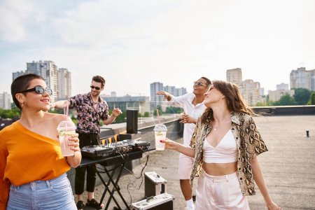 cheerful interracial friends with sunglasses drinking alcohol at rooftop party and dancing to DJ set