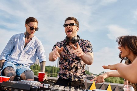 joyeux beaux gens en tenue décontractée avec des lunettes de soleil faire la fête sur le toit au DJ set