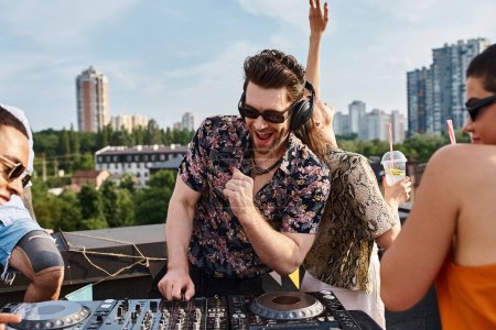 Foto de Amigos alegres multiculturales con gafas de sol de moda que se divierten en la fiesta en la azotea bailando para DJ conjunto - Imagen libre de derechos