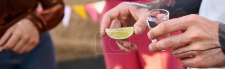 cropped view of young friends in urban attires preparing to drink tequila with lime and salt, banner