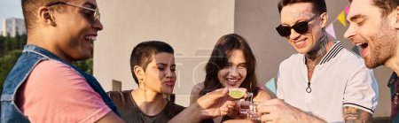 Téléchargez les photos : Amis joyeux multiculturels boire de la tequila avec du citron vert frais et du sel à la fête sur le toit, bannière - en image libre de droit