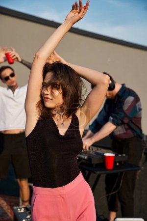focus on cheerful long haired woman in urban attire partying next to her jolly blurred friends