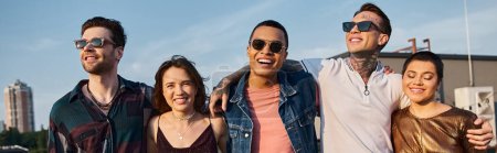 Foto de Alegre gente diversa en trajes urbanos con gafas de sol que se divierten y sonríen en la cámara, pancarta - Imagen libre de derechos